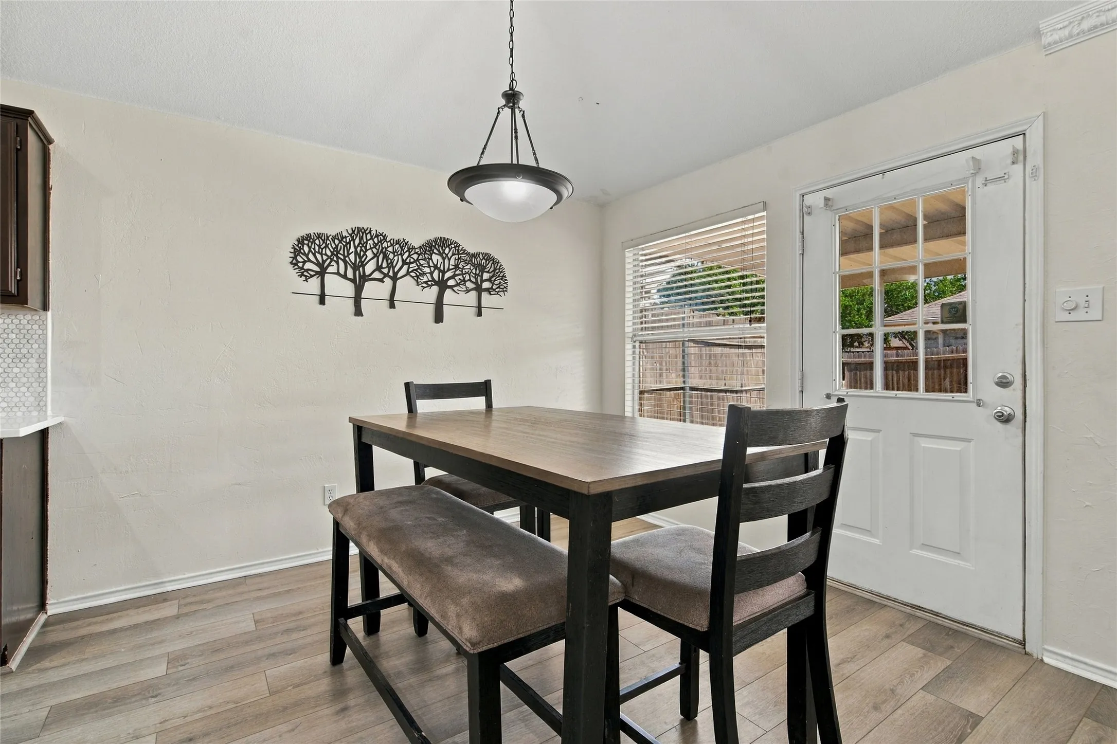 Wood-finish flooring with white baseboards, pendant light fixture, and window with blinds