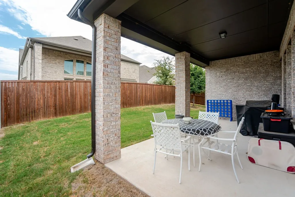 Covered patio featuring concrete flooring, brick columns, and a dark soffit