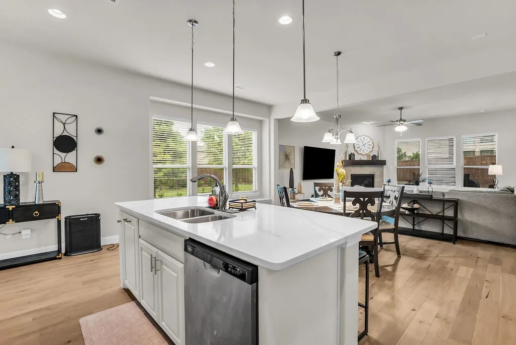 Kitchen island with a double basin sink, integrated dishwasher, and pendant lighting
