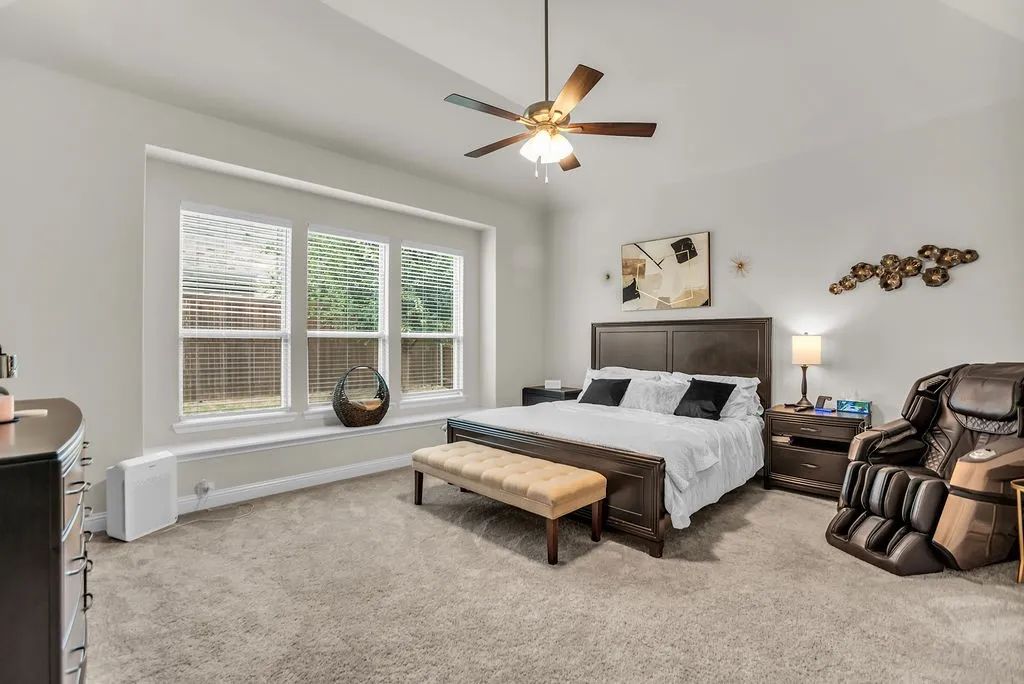 Vaulted ceiling featuring a ceiling fan, plush carpet, and a window seat with three windows