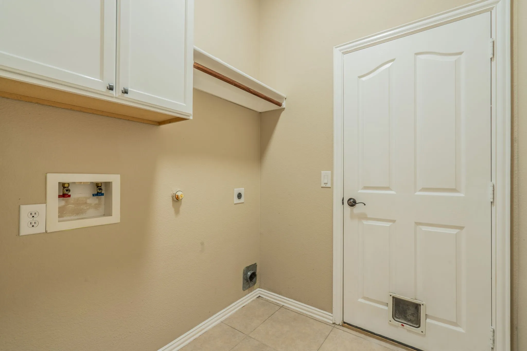 White shaker-style cabinetry with dark hardware, a built-in hanging rod, and tile flooring