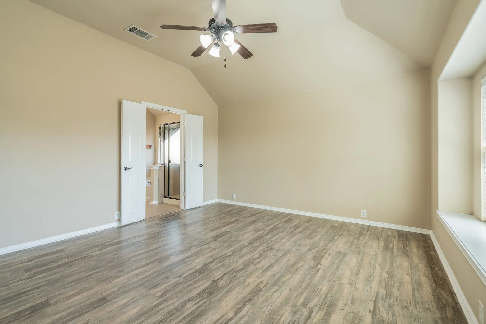 Vaulted ceiling with a ceiling fan, wood-finish flooring, neutral wall tones, window with sill, and French doors
