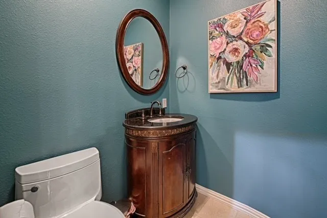 Pedestal vanity with an integrated sink, dark countertop, and decorative wood-finish base
