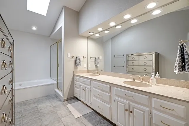 Dual vanity with under-mount sinks, light-toned countertop, and extensive cabinetry