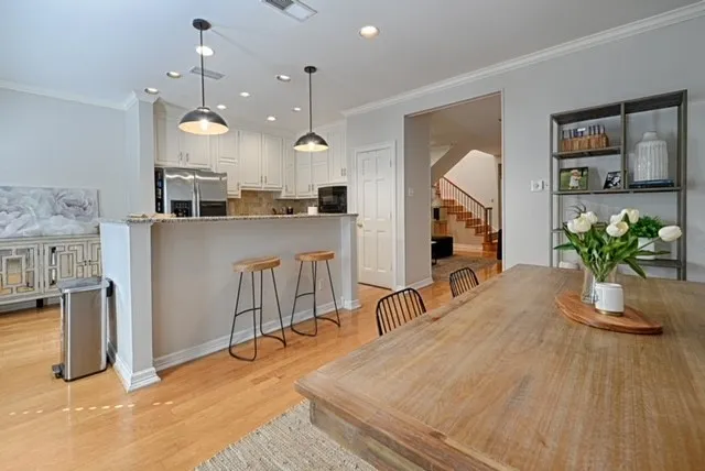 Hardwood flooring, crown molding, recessed lighting, kitchen island with seating, and stainless steel appliances