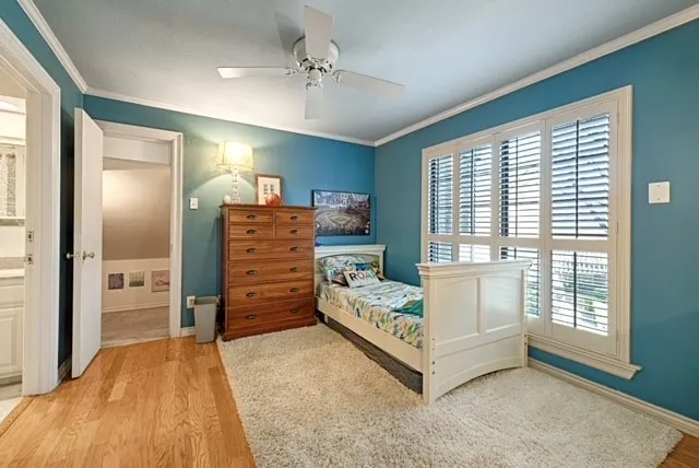 Hardwood flooring, ceiling fan, white window shutters, and white trim