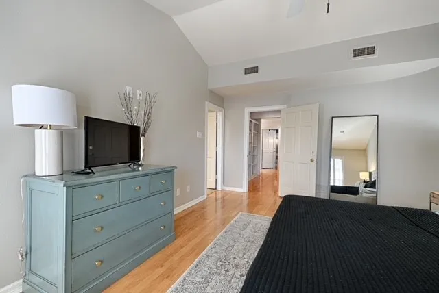 Vaulted ceiling with a ceiling fan, hardwood flooring, and light gray wall paint