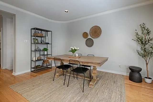 Recessed ceiling lighting, crown molding, wood-finish flooring, and white baseboards