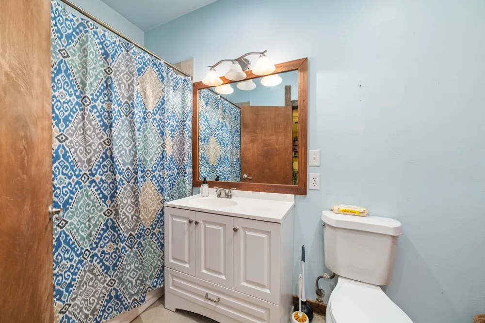 Vanity with a white countertop and base cabinetry, complemented by a framed mirror