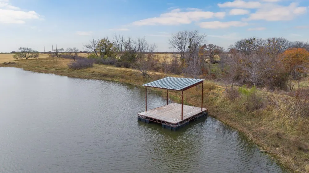 Pond featuring a floating dock with a covered structure