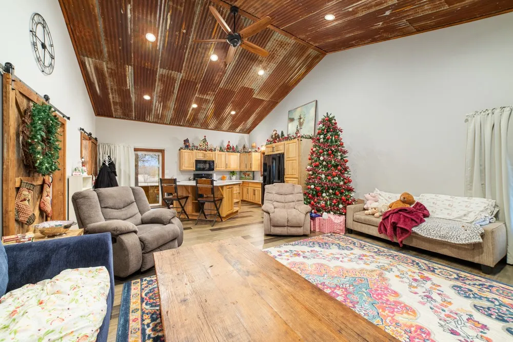 Vaulted ceiling with corrugated metal finish, recessed lighting, and a ceiling fan
