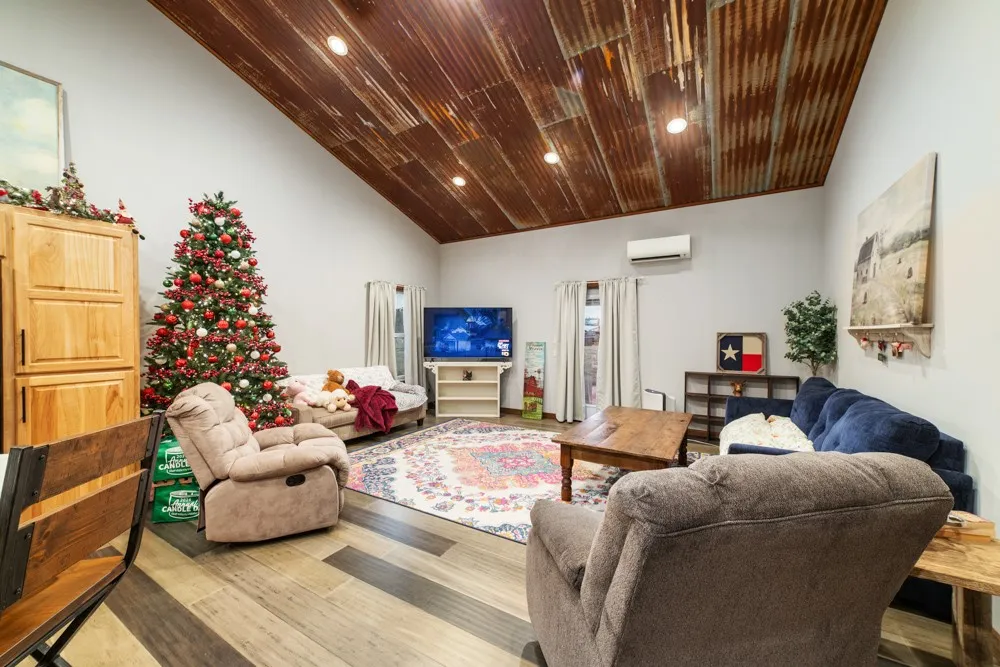 Vaulted ceiling with corrugated metal finish, recessed lighting, wood-finish plank flooring, and light-toned walls