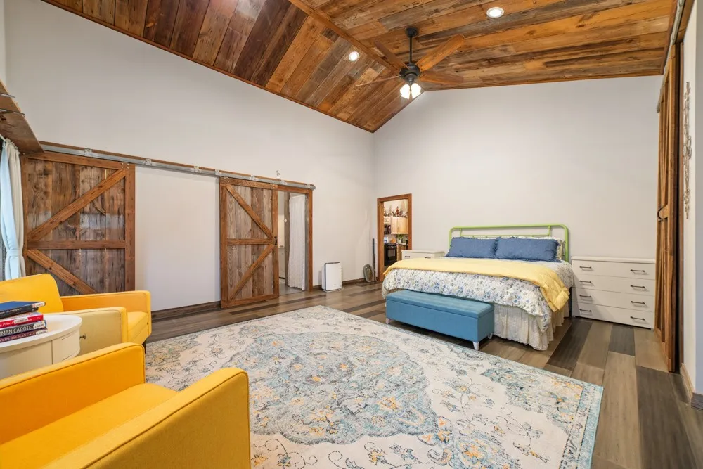Vaulted wood-finish ceiling with exposed beams, wood-finish flooring, and natural wood barn doors
