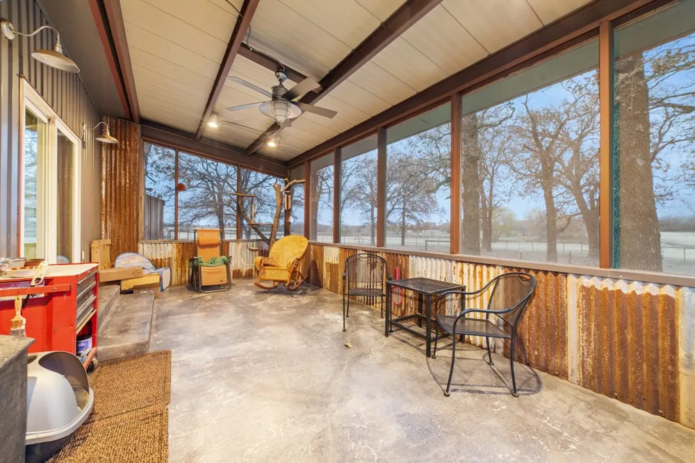 Screened porch with corrugated metal accents, a ceiling fan, and concrete flooring