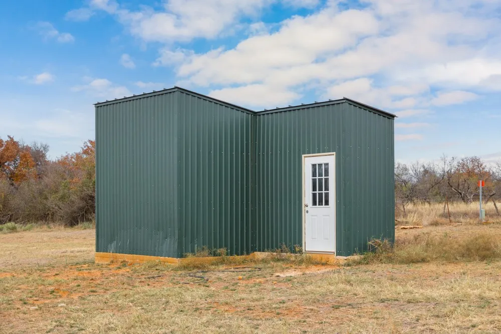 Green corrugated metal structure featuring a white paneled door with grid lites