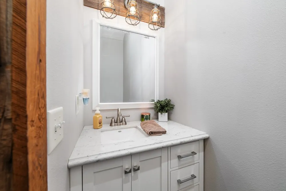 Vanity featuring a rectangular undermount sink, a countertop with a stone-like finish, and a light-toned cabinet with drawers