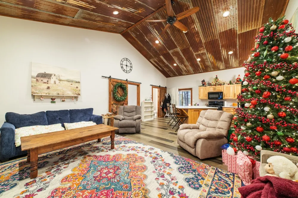 Vaulted ceiling with corrugated metal finish, recessed lighting, wood-finish flooring, and a ceiling fan