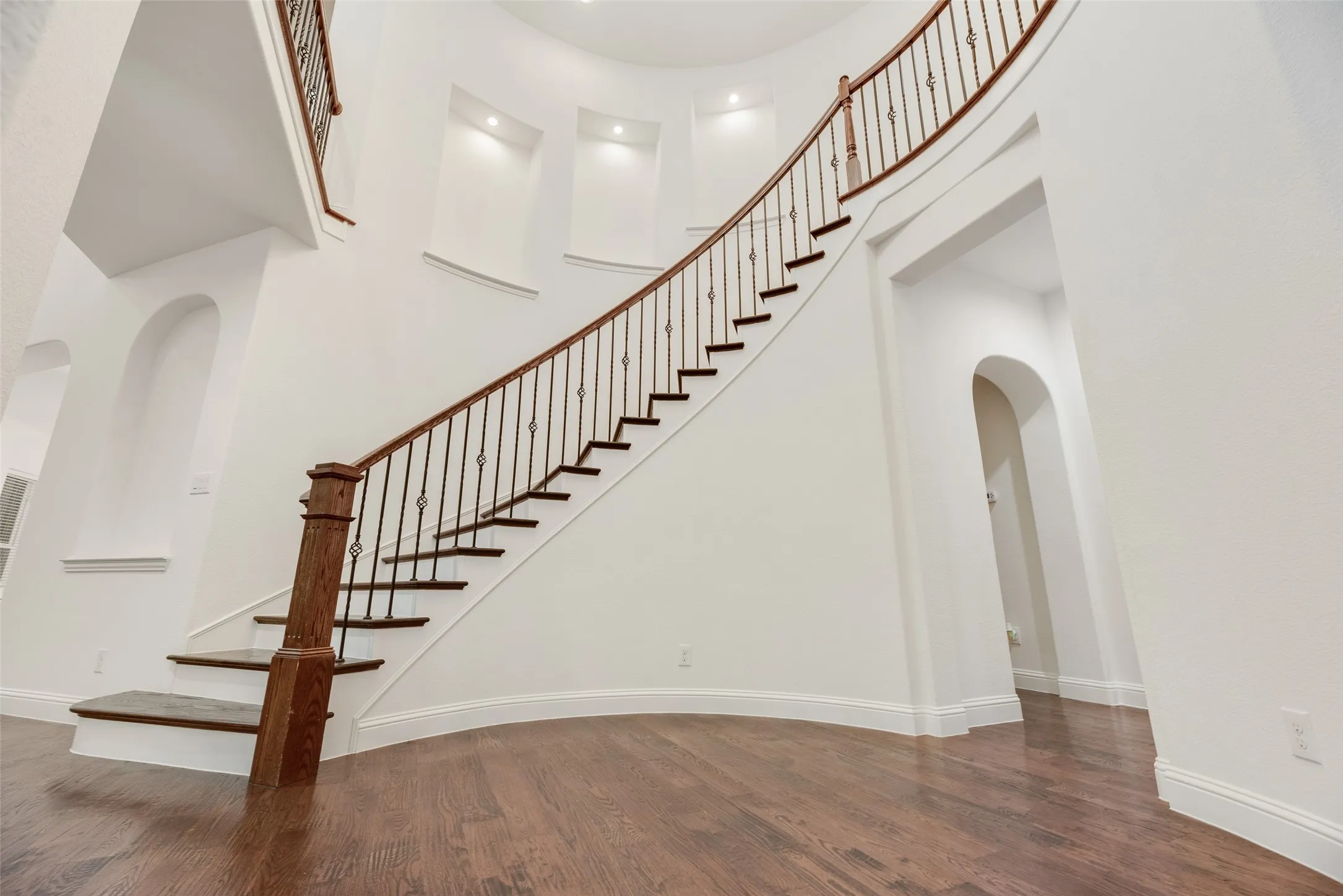 Curved staircase with wood-finish treads and wrought iron balusters