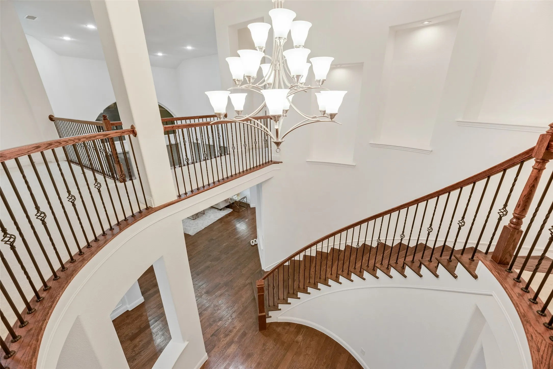 Grand curved staircase with rich wood treads and wrought iron balusters