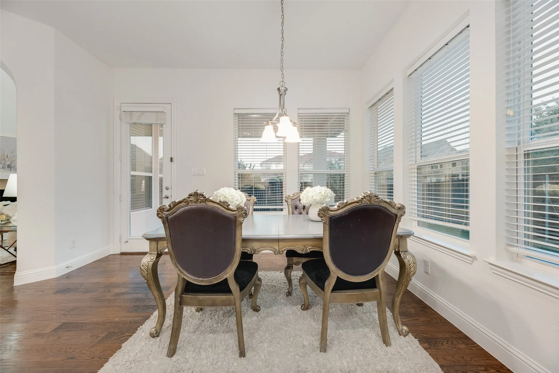 Hardwood flooring, multiple windows with blinds, a built-in archway, and a glass-paneled door