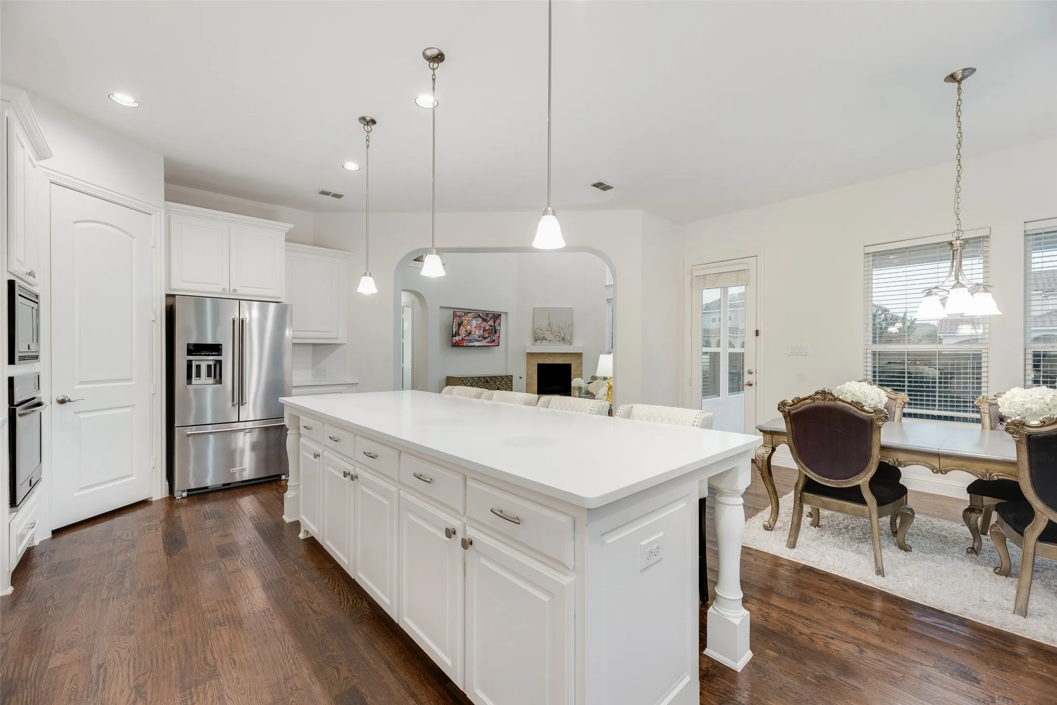 Kitchen featuring an expansive center island with white cabinetry, stainless steel appliances, and dark wood-finish flooring