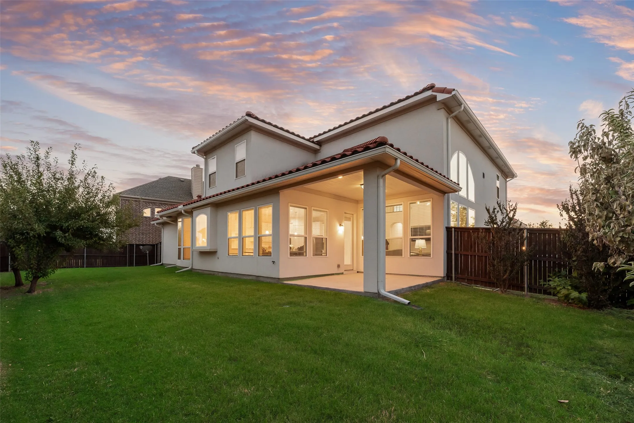 Spacious backyard featuring a covered patio, stucco exterior, tile roof, and a privacy fence