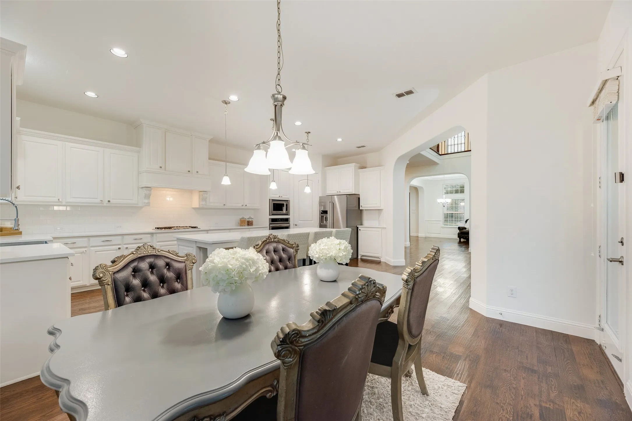 Spacious kitchen featuring white cabinetry, light countertops, subway tile backsplash, and stainless steel appliances