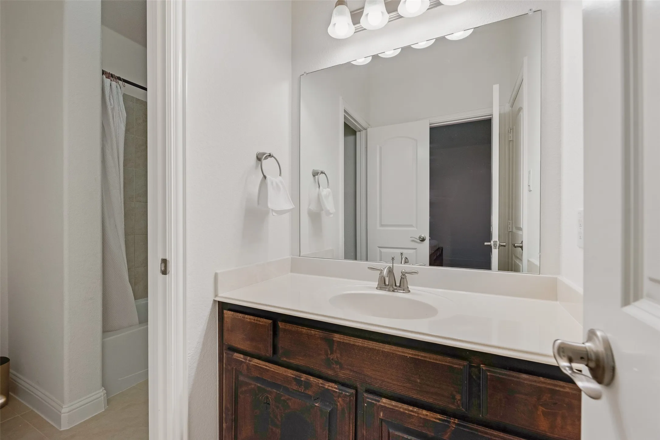 Jack and Jill Bathroom. Vanity with a wood-finish cabinet, light-colored countertop, and integrated sink