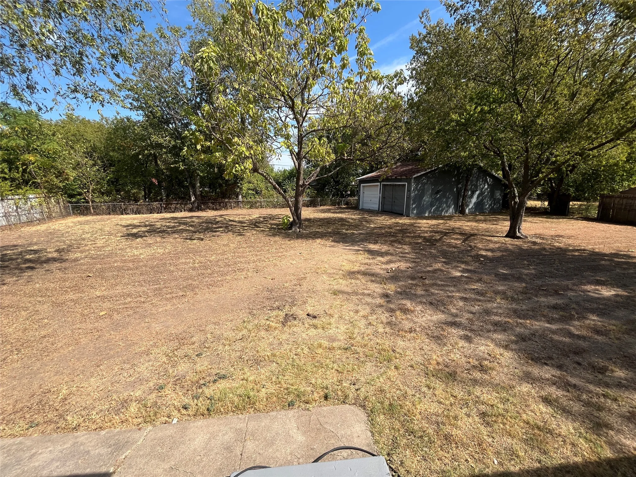 Expansive yard featuring mature trees and a detached two-car garage