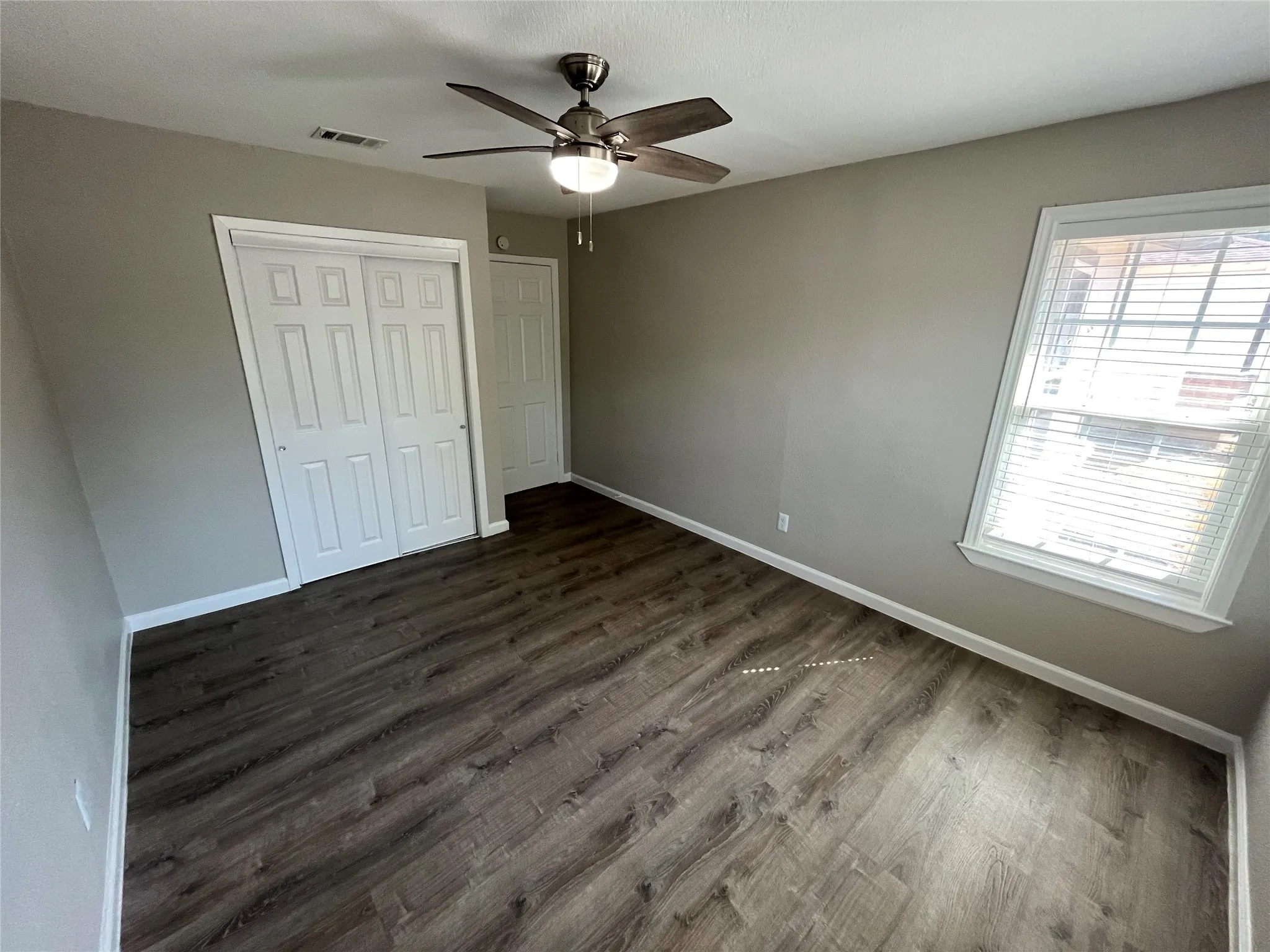 Room featuring wood-finish flooring, neutral wall paint, and a ceiling fan with integrated lighting