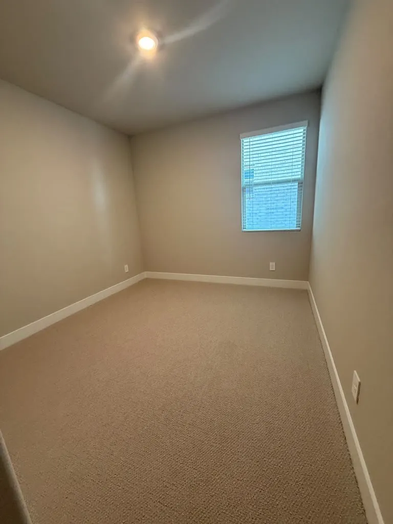Recessed ceiling light, neutral-toned walls, carpeting, and a window with blinds