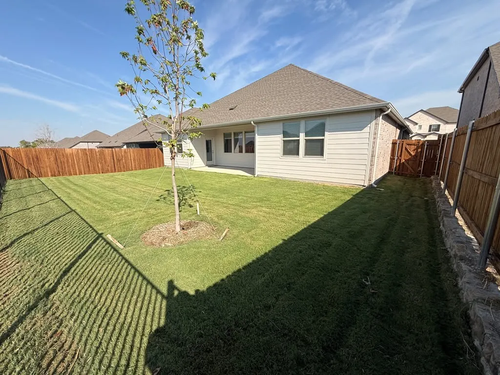 Expansive backyard featuring a manicured lawn, established privacy fencing, and a dedicated patio space
