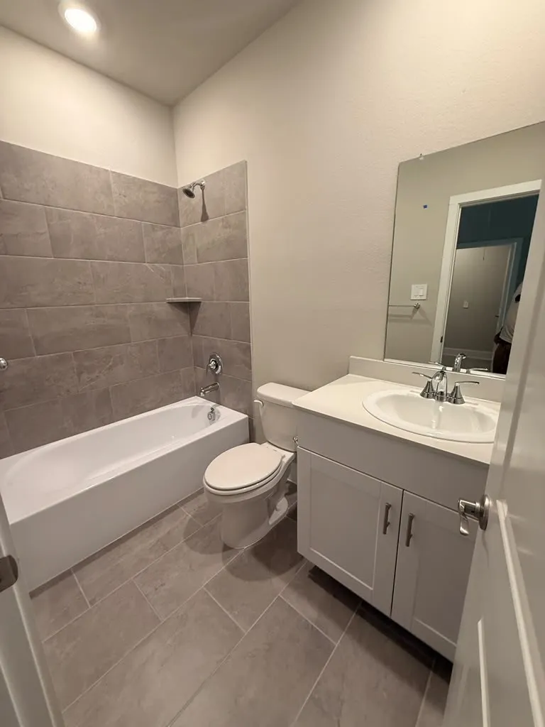 Full bathroom featuring a white vanity with an integrated sink, a white bathtub, and a toilet