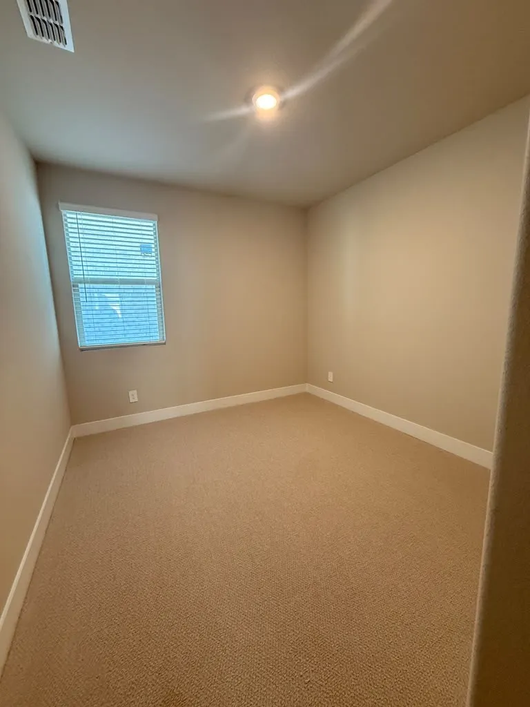 Recessed ceiling light, neutral wall colors, carpeting, and a window with blinds
