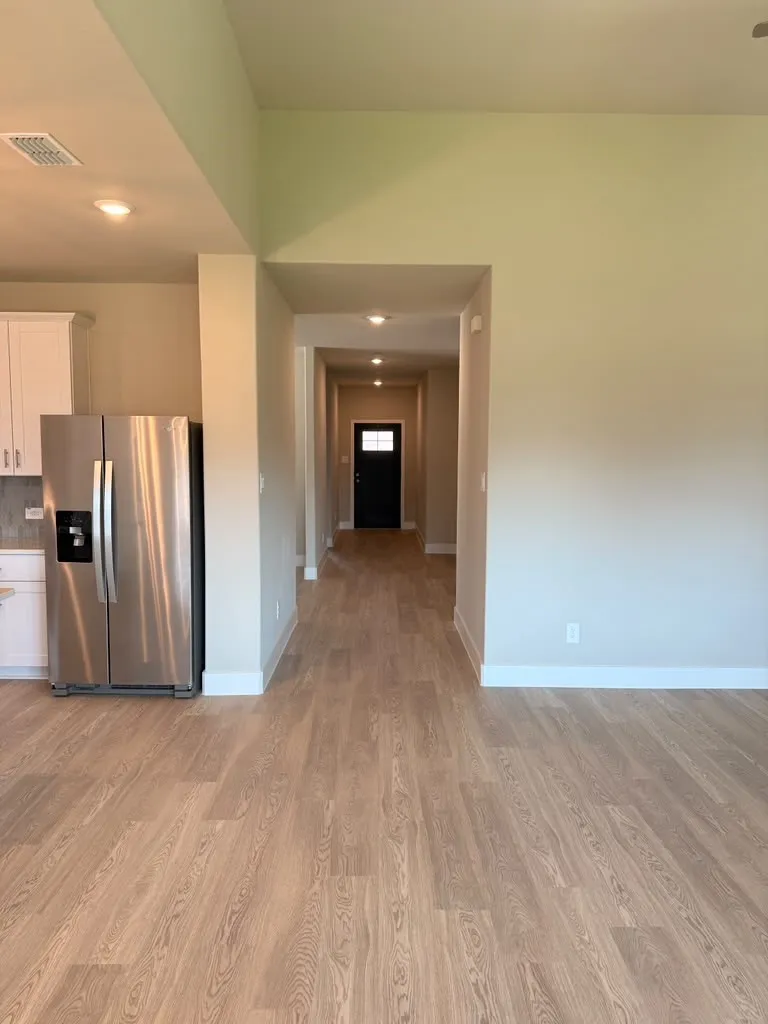 Wood-finish flooring throughout, recessed lighting, and a stainless steel refrigerator