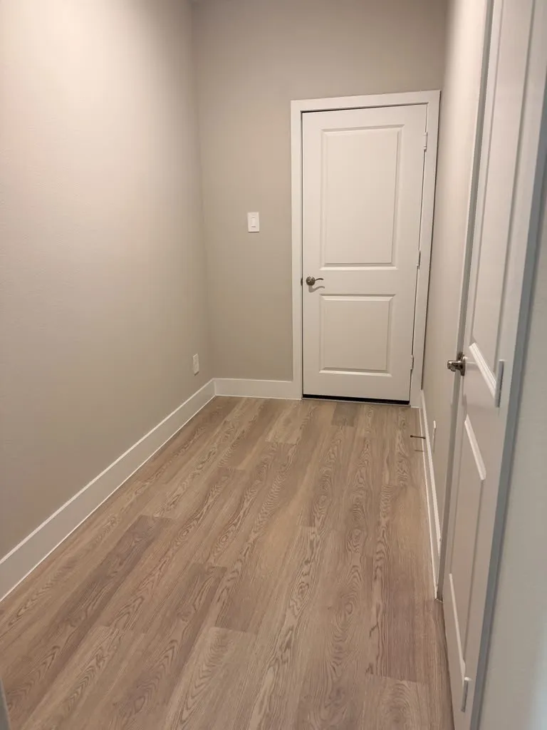 Interior hallway featuring wood-finish flooring and light neutral wall paint