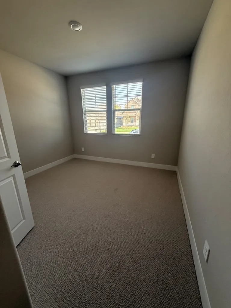 Plush carpeting, neutral wall tones, white trim, recessed lighting, and two windows with blinds