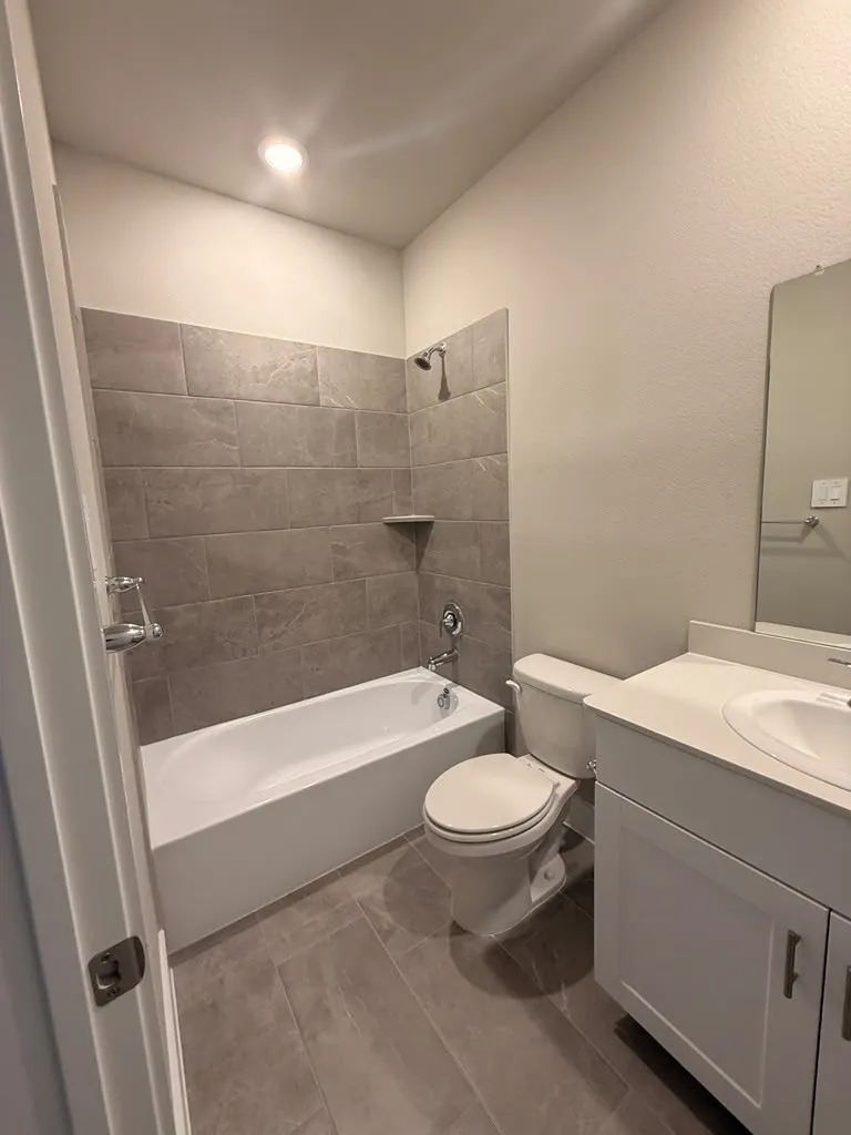 Shower/tub combination with gray tile surround, integrated shower niche, and chrome fixtures