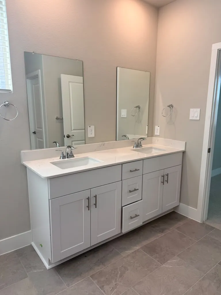Dual vanity with white shaker-style cabinetry, undermount sinks, and light-toned countertops