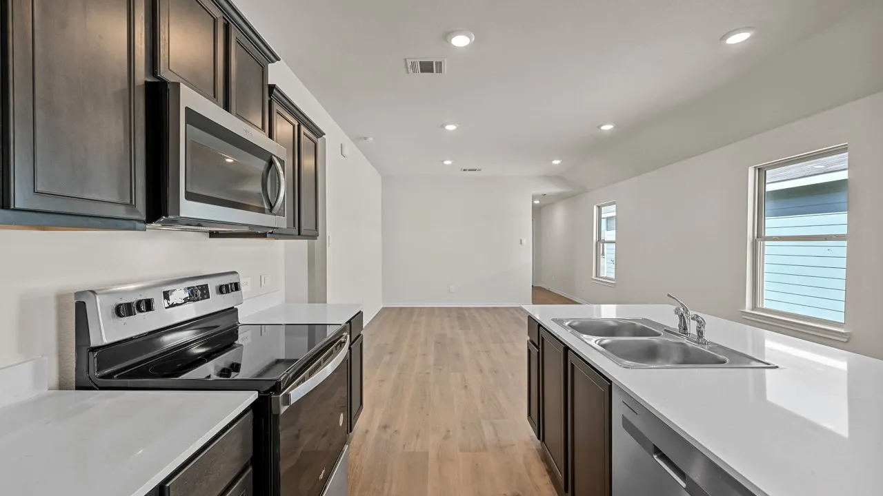 Kitchen featuring dark wood-finish cabinetry, stainless steel appliances, white countertops, a double basin sink, and recessed lighting