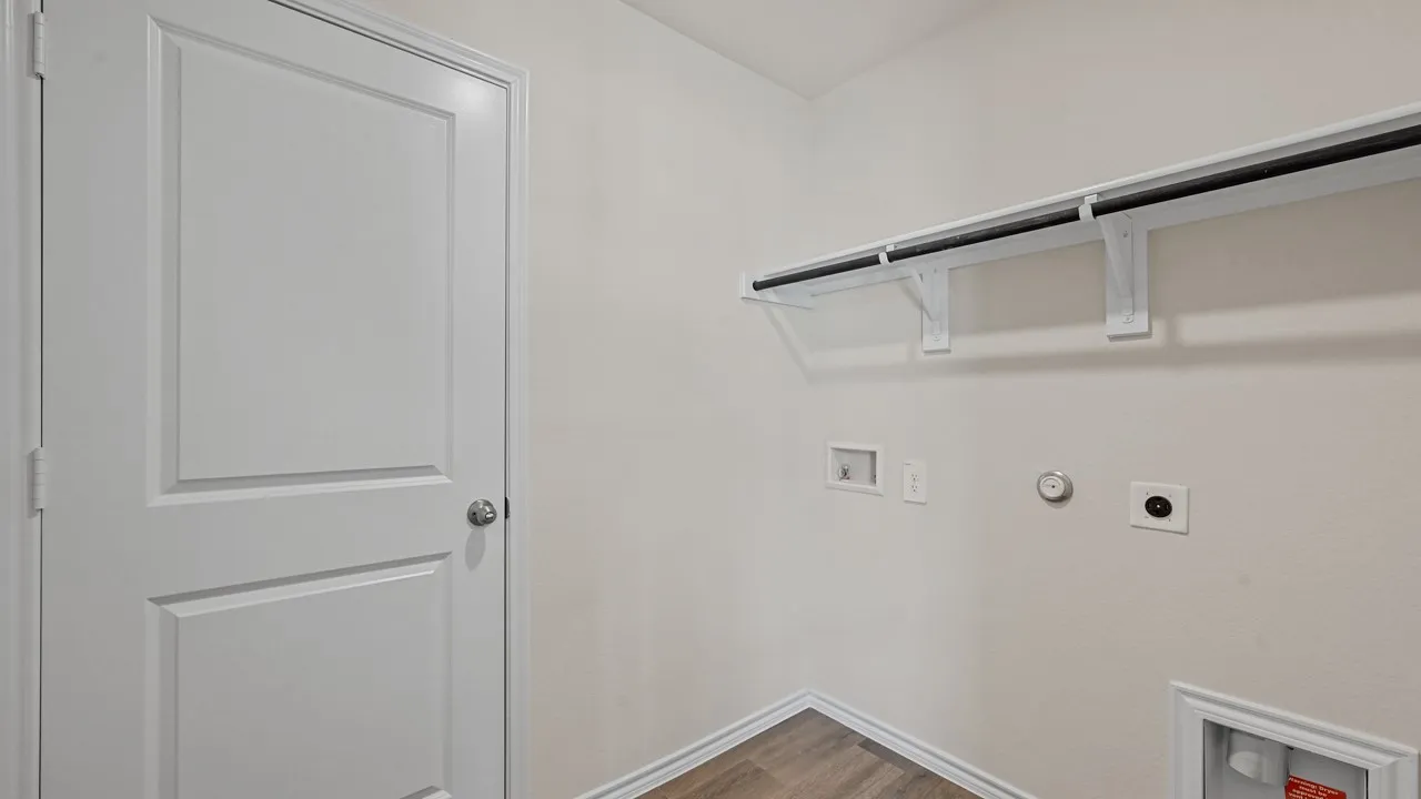 White paneled door, wood-finish flooring, and a mounted shelf and clothing rod