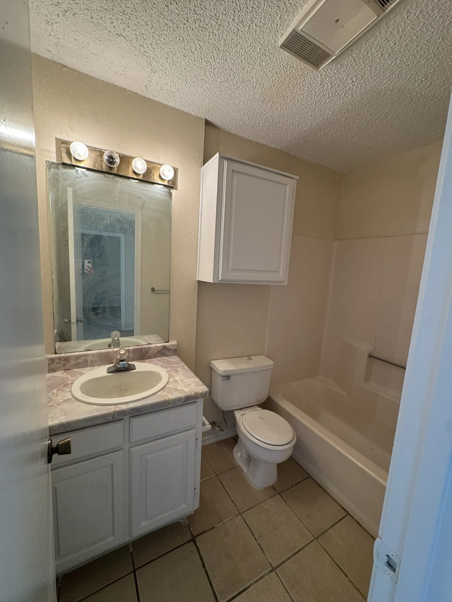 White vanity with a single basin sink and a patterned countertop