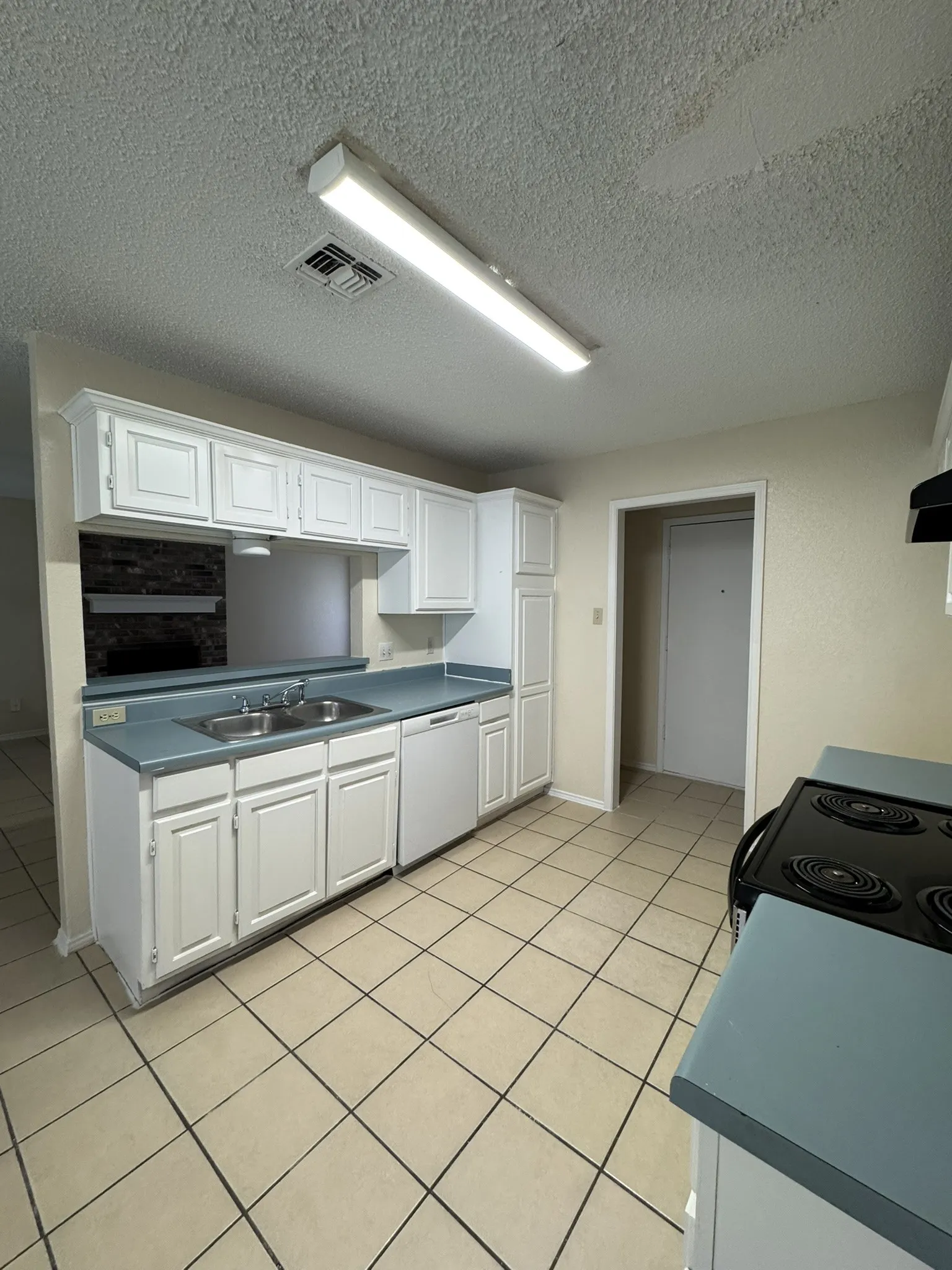 Kitchen featuring white cabinetry, light countertops, dual basin sink, integrated dishwasher, and tile flooring