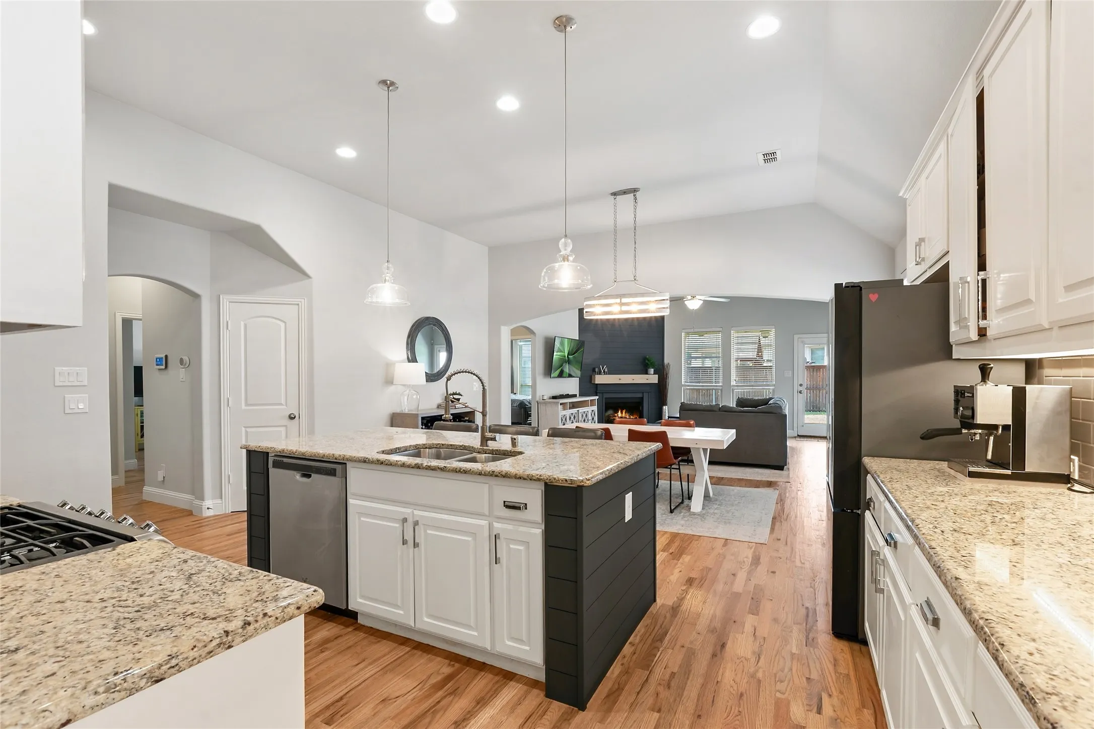 Kitchen with granite countertops, wood-finish flooring, white cabinetry, a central island, and stainless steel appliances