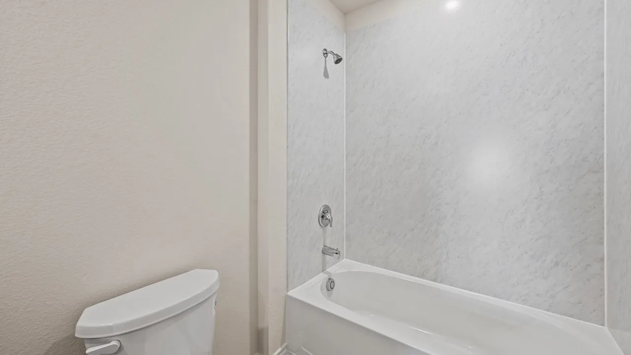 White porcelain bathtub with a coordinating shower surround and chrome fixtures