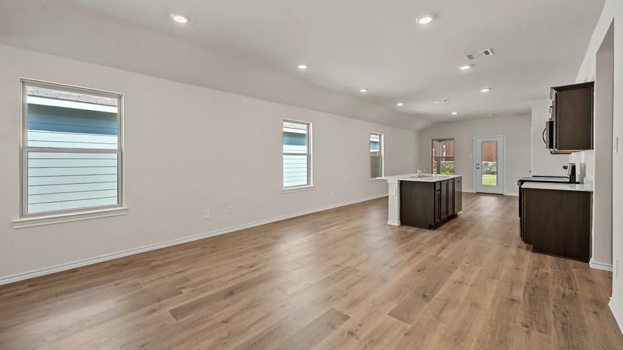 Open-concept living area featuring wood-finish flooring, recessed lighting, and ample natural light from multiple windows