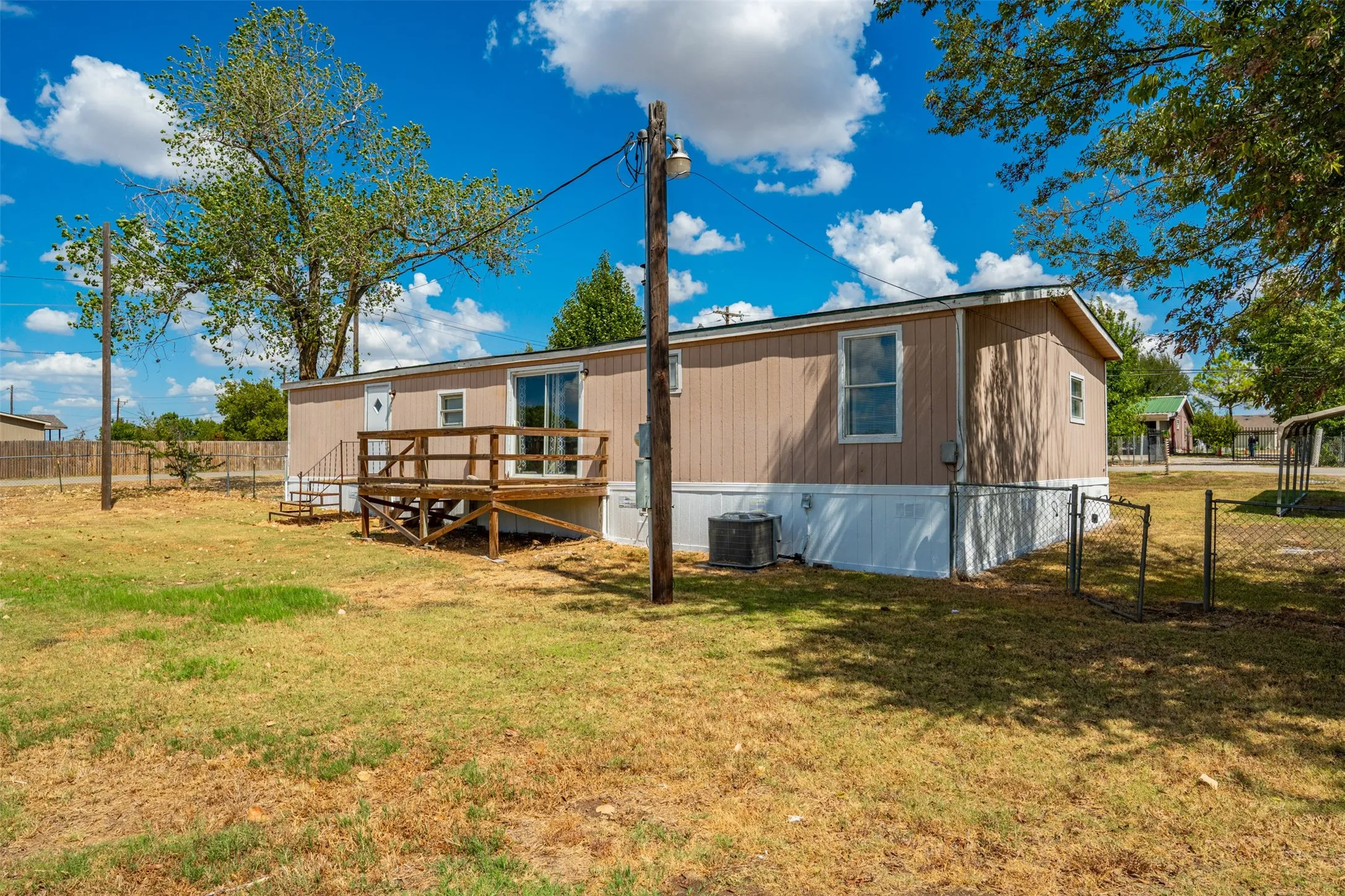 Siding exterior with a built-in wood deck, sliding glass door, and multiple windows