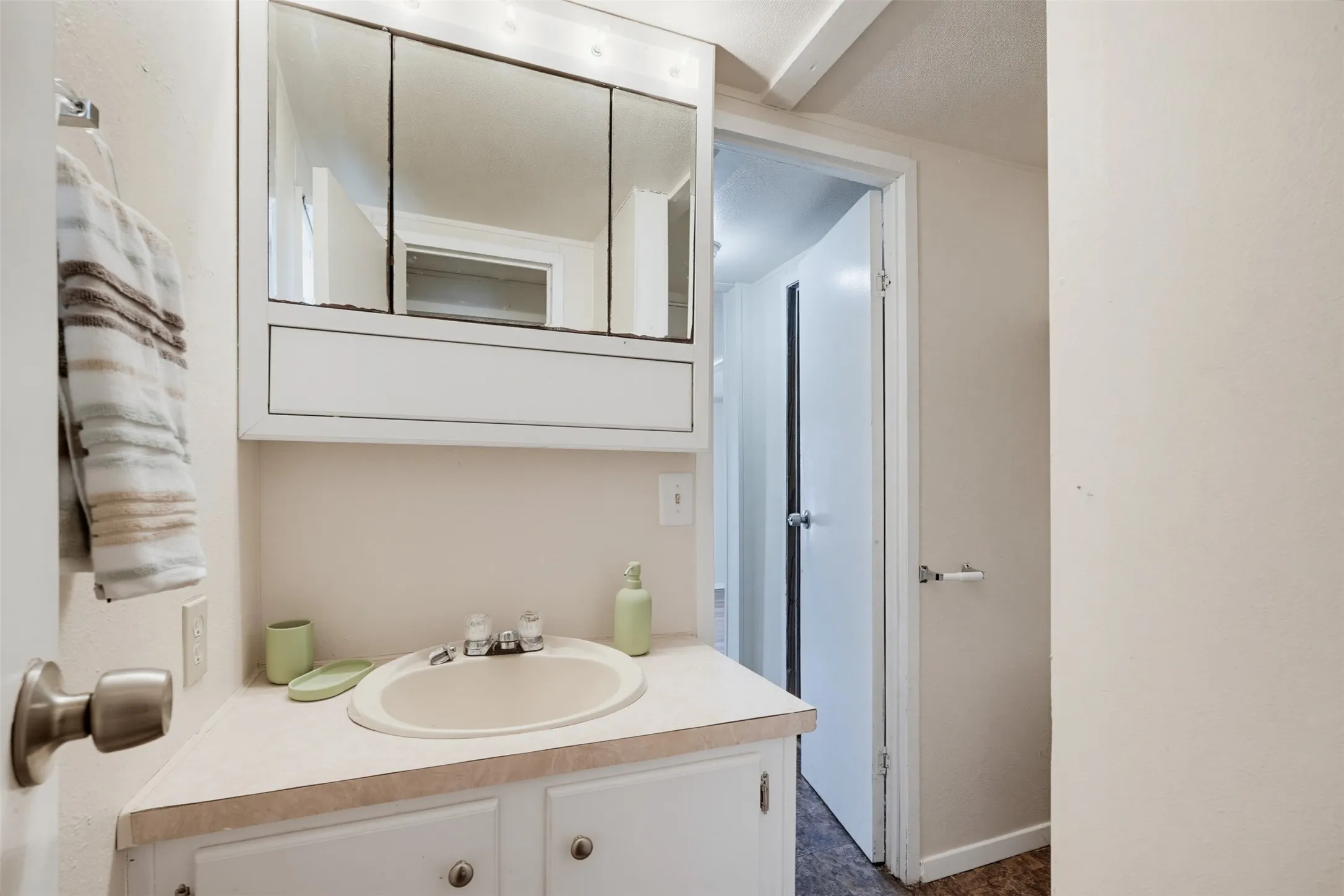 White vanity with integrated sink, laminate countertop, and medicine cabinet with mirrored doors