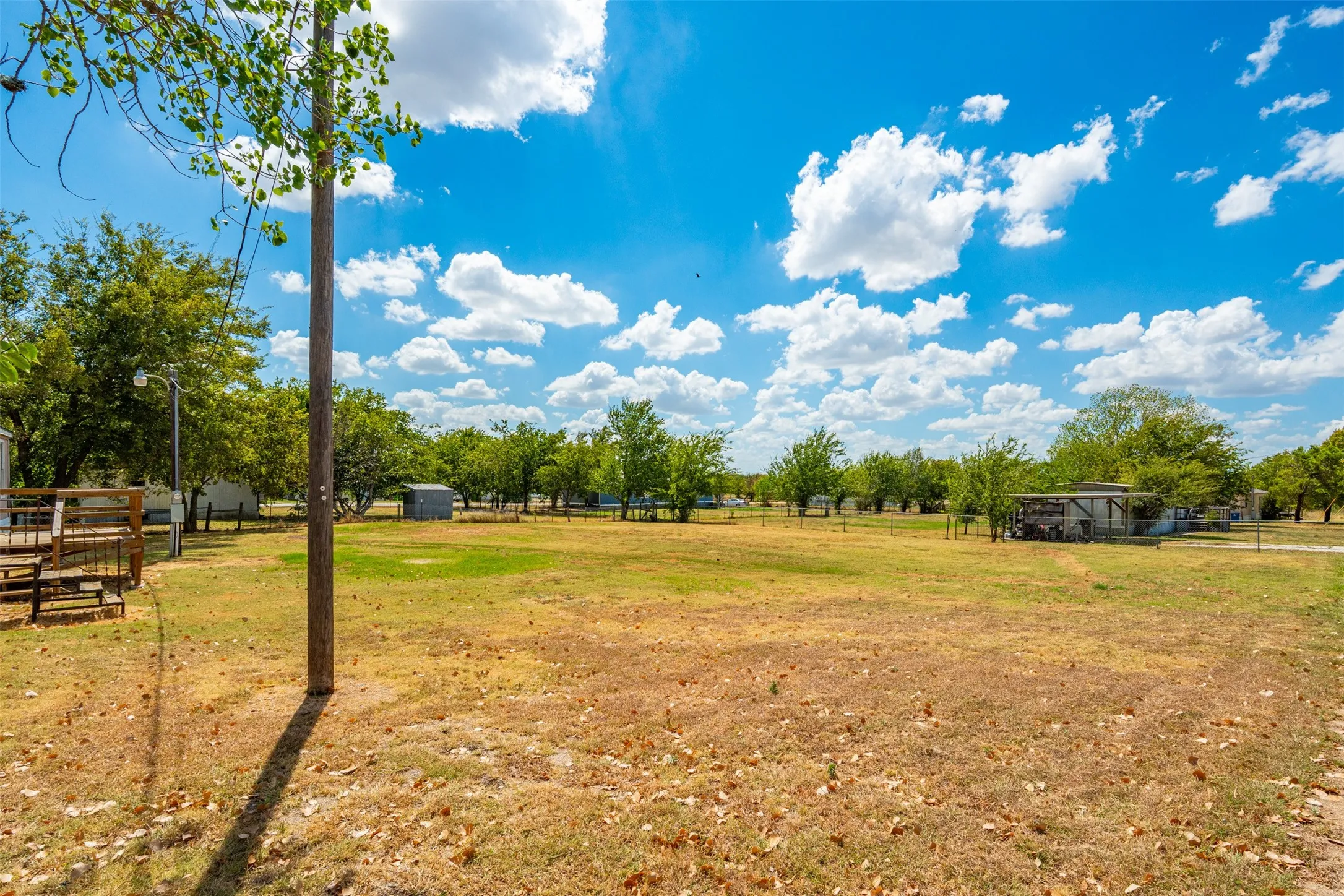 Expansive lot featuring mature trees and a clear blue sky
