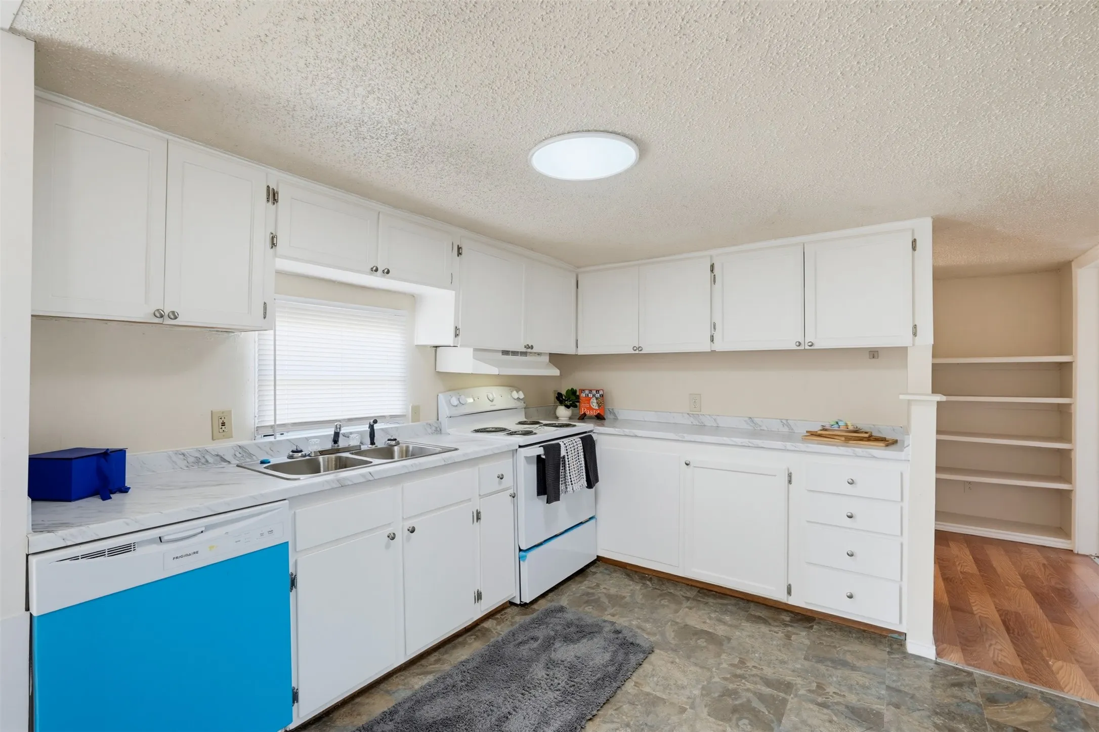 Kitchen featuring white cabinetry, a double basin stainless steel sink, a built-in dishwasher, an electric range, and ample countertop space